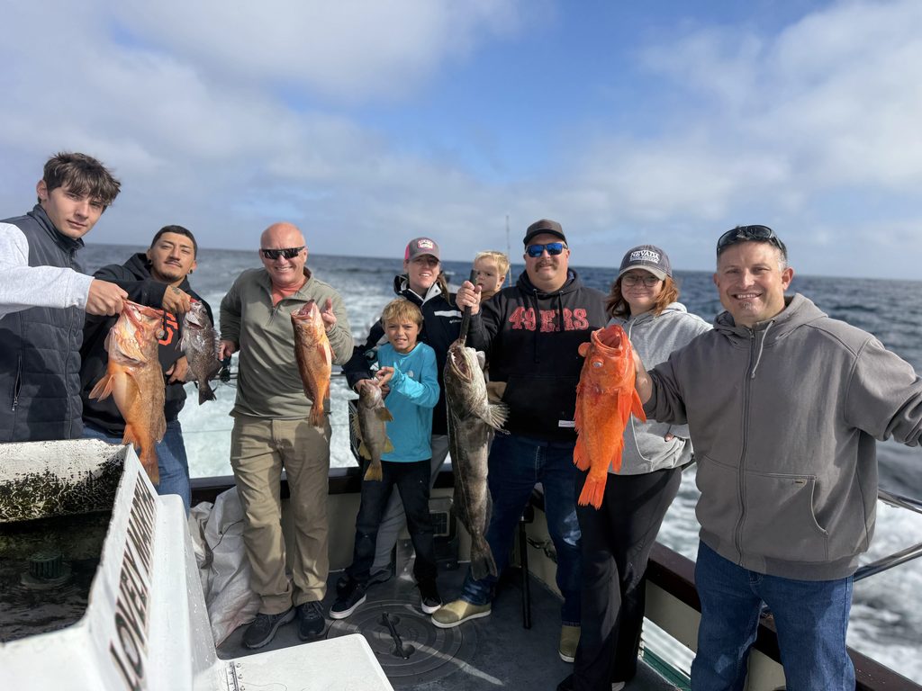 IMG_20260904_153823 1 | TechCity Electric Group of people on a boat proudly holding large red-orange fish they just caught with the ocean in the background.